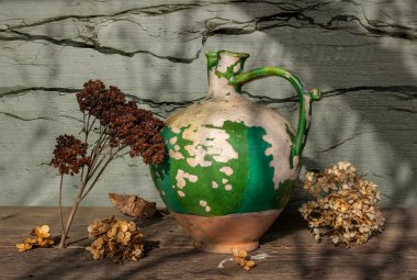 Çok eski seramik sürahi, kabuğu soyulmuş boya ve kurumuş çiçekler. Eski.