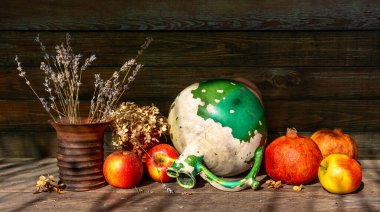 Çok eski bir seramik sürahi, soyulmuş boya, kurutulmuş çiçeklerden oluşan seramik bir vazo, olgun elmalar ve nar. Eski.