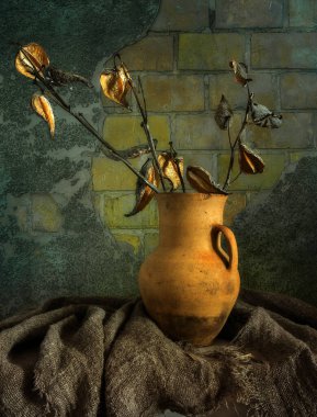 Çuval bezle kaplı bir masanın üzerinde kurumuş dalları olan eski bir seramik sürahi. Eski model. Retro.