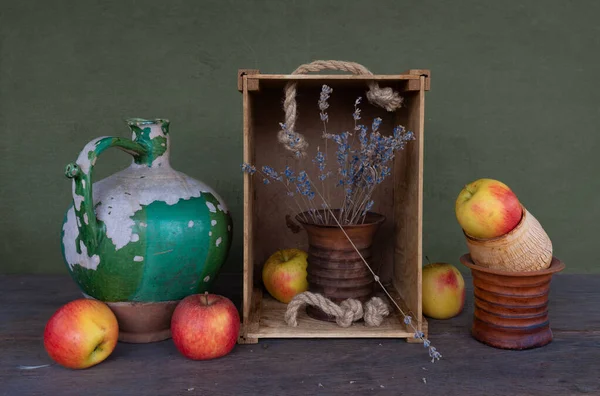 Eski bir seramik sürahi, soyulmuş boya, seramik bir vazo, kurumuş çiçekler ve olgun elmalarla dolu bir hayat. Eski.