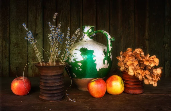 Çok eski bir seramik sürahi, soyulmuş boya, iki seramik vazo kurutulmuş çiçek, ve olgun elmalar. Eski.