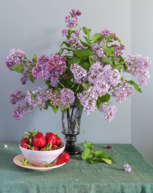Güzel bir buket taze kokulu leylak, olgun ve lezzetli çilek.