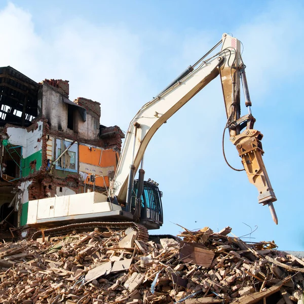 Excavator demolishing a brick building. Machinery Demolishing Building Stock Image