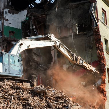 Kazıcı tuğla bir binayı yıkıyor. Makine Yıkım Binası