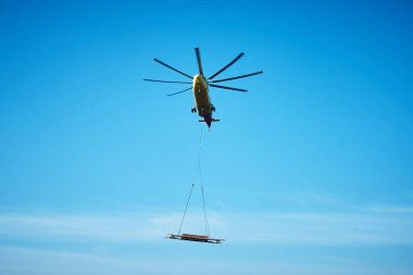 Dünyanın en büyük kargo helikopteri tepemizde uçuyor. Alt görüntü. Dünyanın en büyük kargo helikopteri kargoyu tel bir iple taşıyor. Alt görünüm.