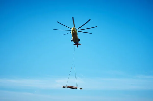 Dünyanın en büyük kargo helikopteri tepemizde uçuyor. Alt görüntü. Dünyanın en büyük kargo helikopteri kargoyu tel bir iple taşıyor. Alt görünüm.