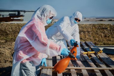 Koruyucu giysili insanlar şehrin sokaklarında dezenfekte oluyor. Salgın korona virüsü, dünya çapında salgın. Karantinadaki virüslerden kaynaklanan yüzeylerin dezenfekte edilmesi. Dezenfektan sıkarak..