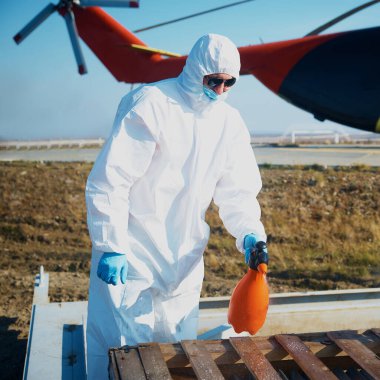 Takım elbiseli, eldivenli, maskeli bir çalışan havaalanında yüzey temizliği yapıyor. Havaalanında sterilizasyon.