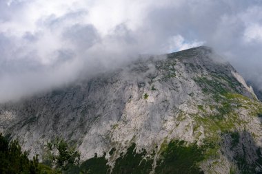 Gökyüzüne ve bulutlara uzanan görkemli beyaz kayalık dağ