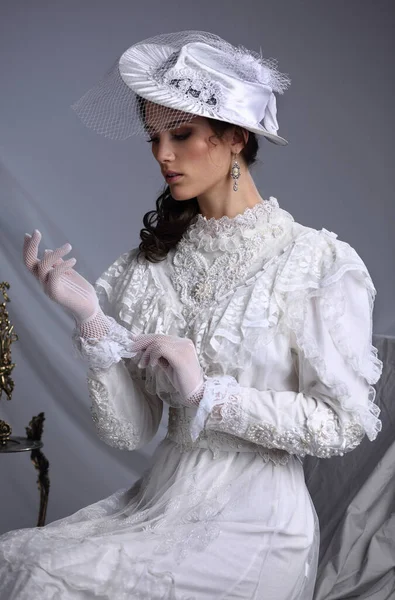 Stüdyo, 19. yüzyıl elbisesi giymiş güzel bir kızın sahnelenmiş portresi.