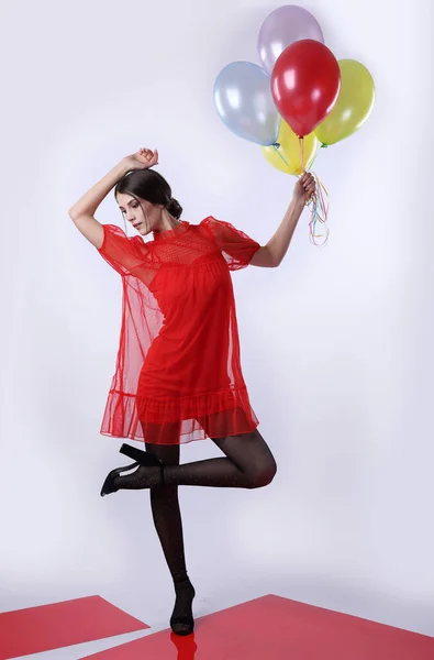 赤いドレスの女の子と明るい背景に風船と黒のタイツ — ストック写真