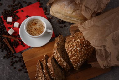 Masanın granit dokusunda kağıt torbalarda beyaz bir fincan kahve ve ekmek ile sakin bir hayat.