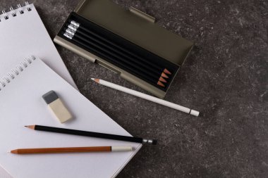 Çizim defteri, kalem kutusu ve masanın granit dokusunda silgi.