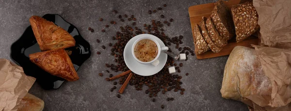 Large-format panorama with a cup of coffee, bread and confectionery on the granite texture