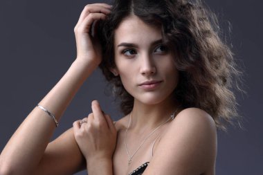 Gri bir arka planda çıplak omuzlu güzel bir kızın stüdyo portresi.