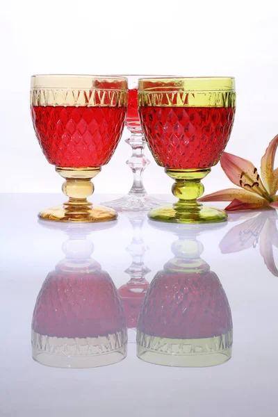 Ποτήρια Κόκκινο Κρασί Και Άνθος Κρίνου Λευκό Γυαλιστερό Τραπέζι — Φωτογραφία Αρχείου