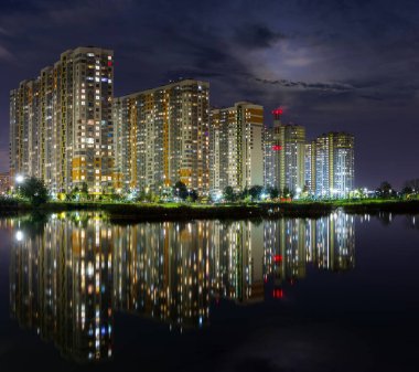 Gölün üzerinde yansıması olan modern evlerin olduğu gece panoraması.