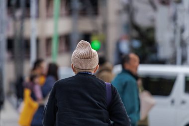 Son sınıf öğrencisi bronzlaşmış yün örgü şapka ve sıcak mavi süveter, yılın ilk duası için Japonya 'nın yeni yıl şapkası sırasında bir geçitte bekleyen bir gruba doğru yürür..
