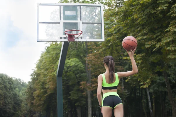 Sportig tjej står tillbaka och kastar bollen in i ringen — Stockfoto