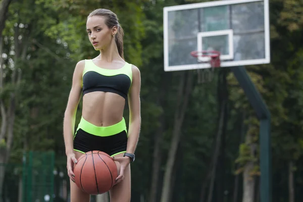 Deportiva chica de pie con una pelota de baloncesto — Foto de Stock