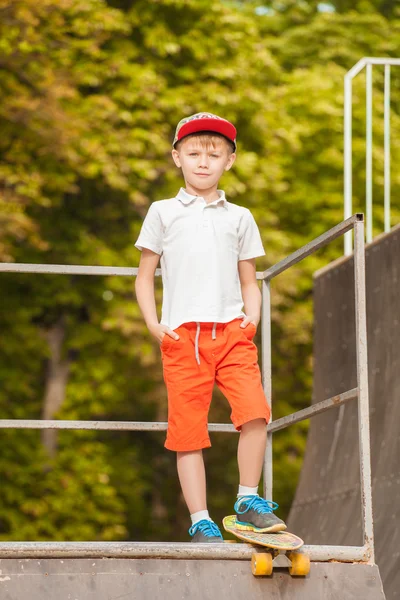 Il ragazzo col berretto in piedi su uno skateboard — Foto Stock