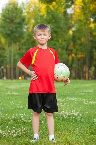 Chlapec s míčem je na pozadí trávy — Stock fotografie