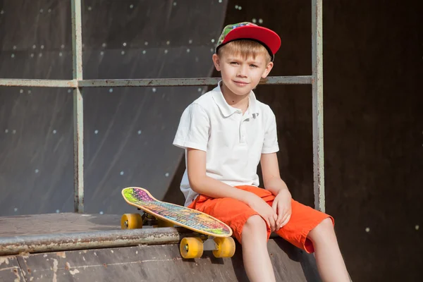 Junge mit Mütze sitzt am Brett und blickt mit einem Lächeln — Stockfoto