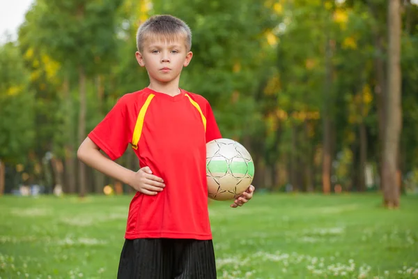 Chlapec s míčem je na pozadí trávy — Stock fotografie