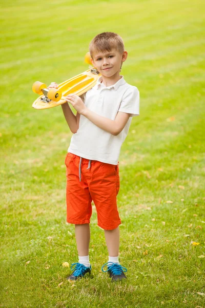 Ragazzo in piedi con uno skateboard in mano — Foto Stock