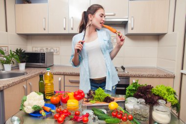 Kız diyet salata hazırlanması sırasında bir havuç yiyor