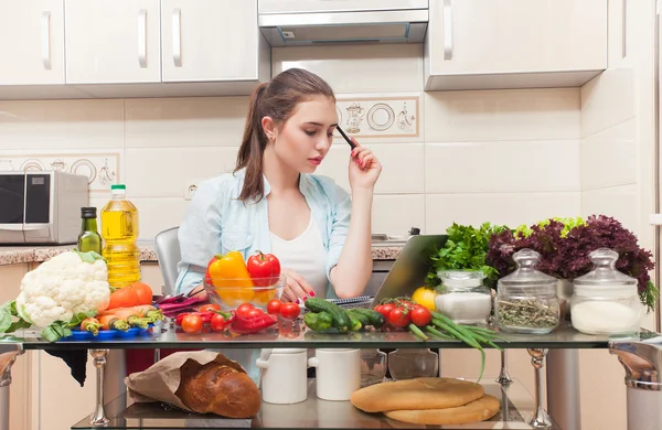 Hermosa chica escribe una receta de ensalada de la computadora portátil — Foto de Stock