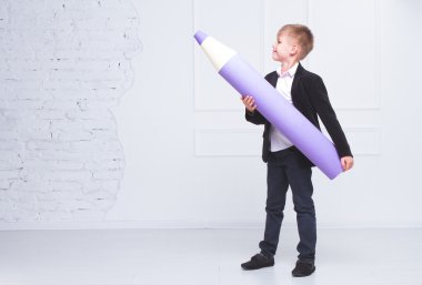 Elinde büyük bir kalem tutan çocuk ve yan onları gösterir