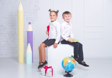 Öğrenciler beyaz arka plan üzerinde oturup gülümseyerek