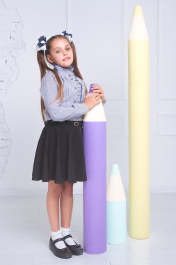 Kız büyük kalemler ile beyaz bir arka plan üzerinde büyük kalem tutan