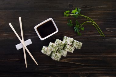 Ahşap arka planda suşi rulo . Onlar 8 adet idi. Sopaların yanına koyun ve soslu yemekler. Lezzetli ve sağlıklı .