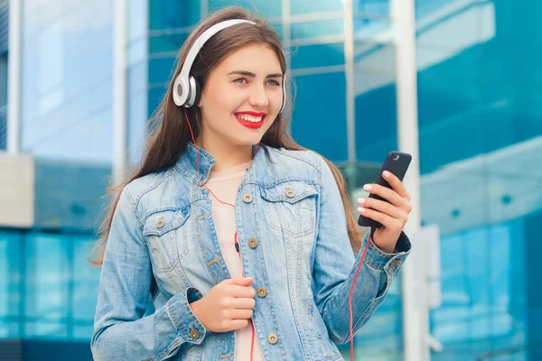Девушка с милой улыбкой слушает музыку в наушниках — стоковое фото