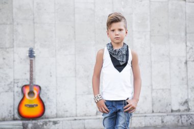 küçük bir çocuk arka plan gitar üzerinde duruyor .