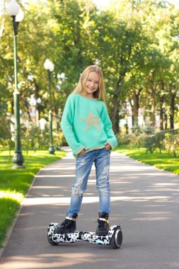 Elektrikli scooter kullanan küçük bir kız ellerini cebine katladı.