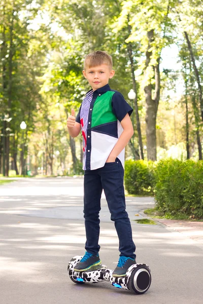 Mały chłopiec jedzie na mini Segway. On jest dobry. Lubi to. — Zdjęcie stockowe