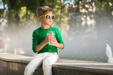 Bir kokteyl elinde tutan şık küçük çocuk. Gözlük takıyor 