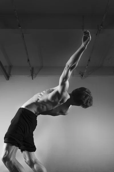 Jonge stong man dansen in de studio. Flexibele body. Vallen. Zwart-wit. — Stockfoto