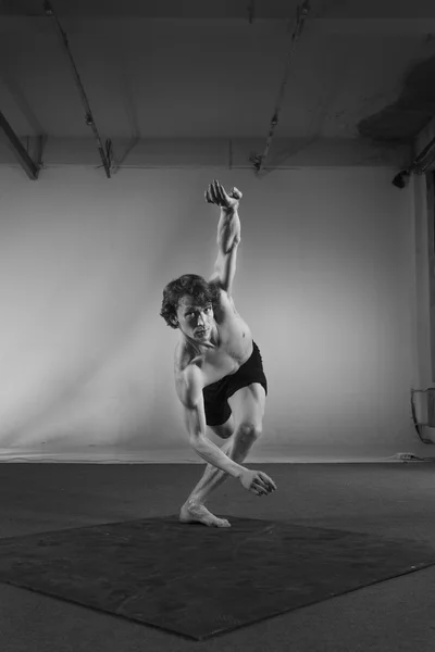 Young stong man dancing in the studio. Flexible body.Black and white.