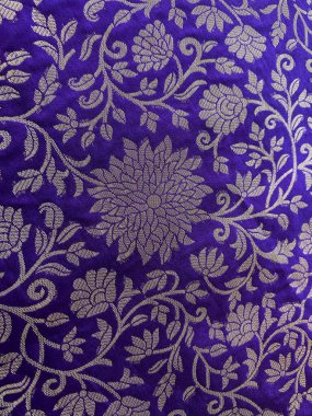 Yakından bakınca, zengin mor ipekten örülmüş karmaşık bir altın çiçekli tasarım, kraliyet işçiliğini ve zamansız bir zarafet duygusunu gözler önüne seriyor.