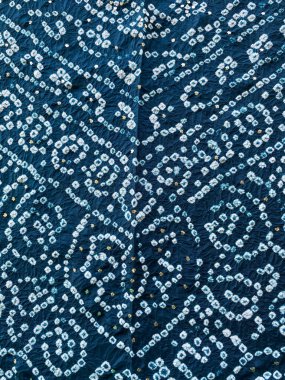 Karmaşık bir geometrik Bandini tasarımı beyaz ve mavi ipek kumaşı süsler, yumuşak metalik bir parıltı sağlayan ince badla işi ile güzelce tamamlanır..