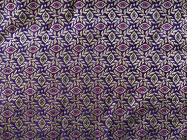 Zengin mor ipekle dokunmuş karmaşık bir geometrik-çiçek deseni. Parıldayan gümüş ipliklerle vurgulanmış. Lüks dokusunu ve incelikli işçiliğini geliştiriyor..