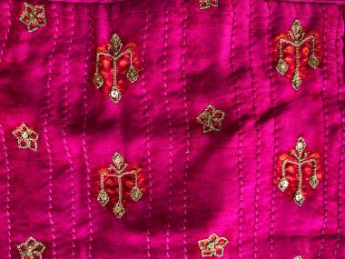 Turuncu elle işlenmiş narin bir altın iplik motifi yumuşak pembe ipek kumaşı güzelce süslüyor, ince zenginlik ve cazibe katıyor..