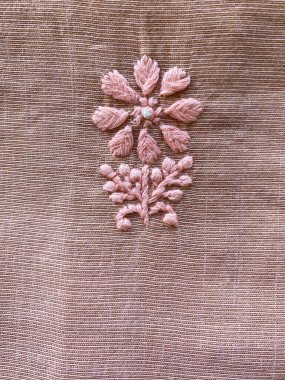 Hassas pembe nakış, ince işçiliği yansıtan pembe doku dokusunda karmaşık bir motif oluşturuyor..