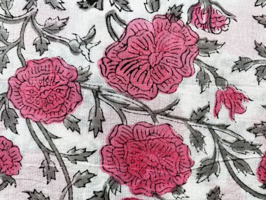 Yakın plan pembe ve gri Jaipur çiçek desenli el bloğu beyaz pamuk kumaşa basılmış.