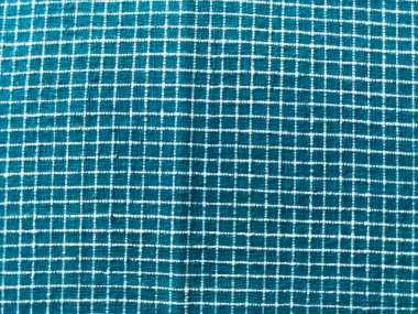 Deniz yeşili pamuk khadi tekstili üzerindeki el yapımı beyaz kareli dokunun doğal dokuma ve zanaatkar işçiliğini gösteren yakın çekimi.