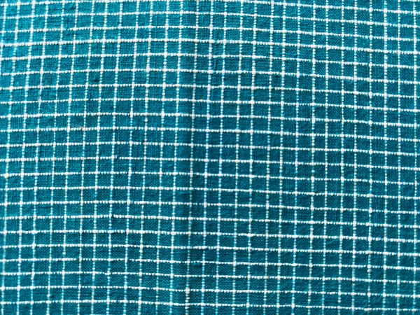 Deniz yeşili pamuk khadi tekstili üzerindeki el yapımı beyaz kareli dokunun doğal dokuma ve zanaatkar işçiliğini gösteren yakın çekimi.